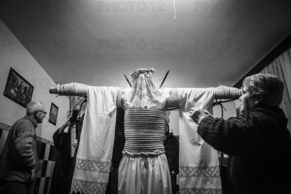 A man is tied to a cross with hemp ropes, he carries two swords in his back, a shroud over them, on his head he wears a crown of thorns, he prepares for the procession of the Empalaos, every Maundy Thursday in Holy Week, Valverde de la Vera, Extremadura, Spain