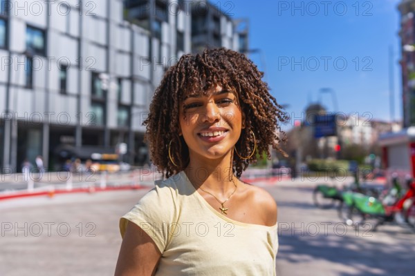 Smiling young woman enjoying a sunny summer day in a vibrant urban setting, surrounded by modern architecture and cheerful energy