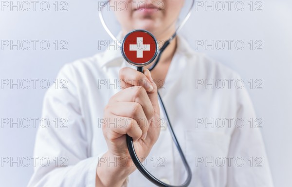 Female doctor holding stethoscope with Switzerland flag. National health system of Switzerland