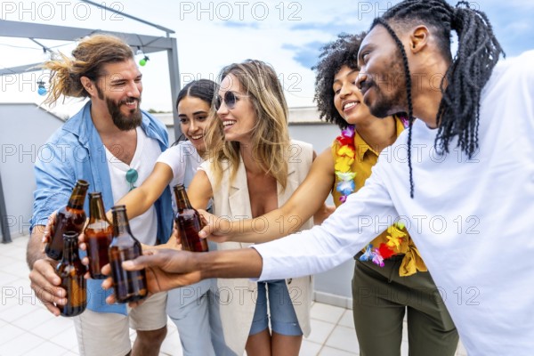 Happy friends celebrating on a rooftop, toasting with beer bottles and enjoying quality time together in a vibrant summer atmosphere