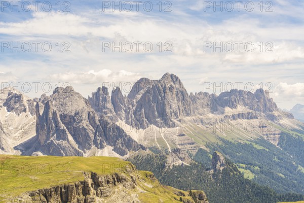 Imposing mountain range with dramatic sky and clouds, green plains below, hike to the Schlehrn, Alpe di Siusi, Dolomites, South Tyrol, Italy
