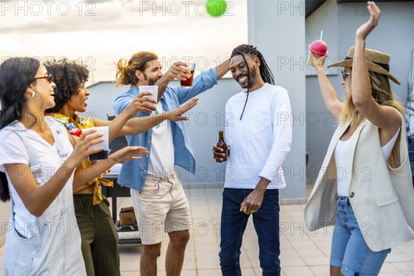 Cheerful young people enjoying drinks and dancing joyfully at a vibrant rooftop party, creating unforgettable memories under the sunset