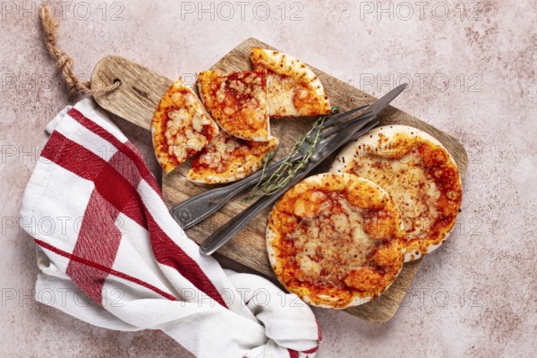 Four pizzetta Margaritas, on a cutting board, on a light gray surface, top view
