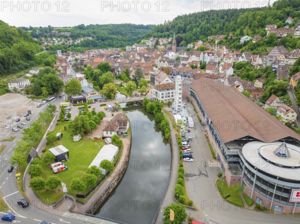 A river runs through the cityscape with a Ferris wheel and environmentally friendly surroundings, surrounded by hills and trees, Ferris wheel construction, Calw, Black Forest, Germany