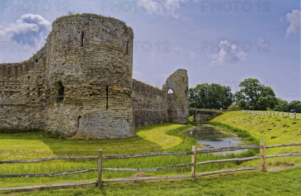 Wall and moat of Pevensey Castle, a Norman castle, in the village of Pevensey, Sussex, England, United Kingdom