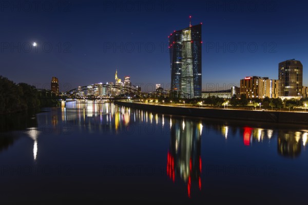 The European Central Bank (ECB) and the Frankfurt banking skyline are reflected in the calm waters of the Main at blue hour, Osthafen, Frankfurt am Main, Hesse, Germany