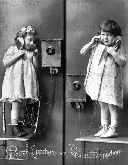 2 girls old telephone chair, Two children telephoning with wall telephones in old-fashioned clothes, Historical photo