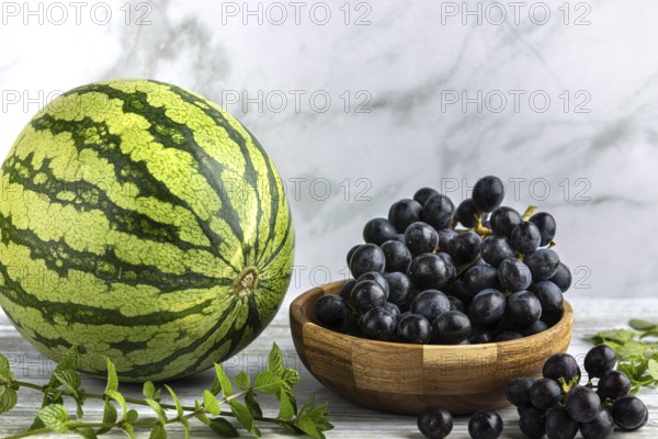 Watermelon with a bowl of grapes and mint in a bright setting