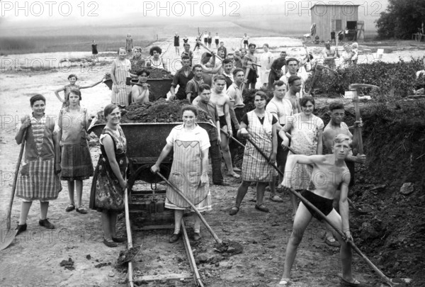 Street child labour shovel shovel apron work clothes earth half-naked Hitler Youth, 1930s, group of men and woman doing hard work on a construction site, historical photo