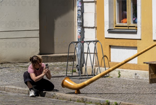 Young woman photographing an alphorn, Potsdam, Brandenburg, Germany