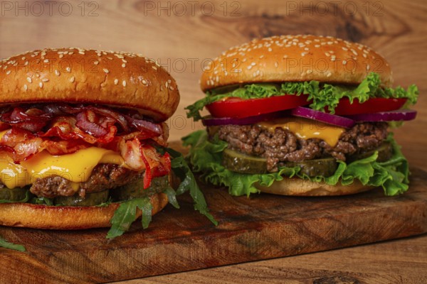 Two burgers with beef patty, fried bacon, cheddar cheese, tomatoes, homemade, no people