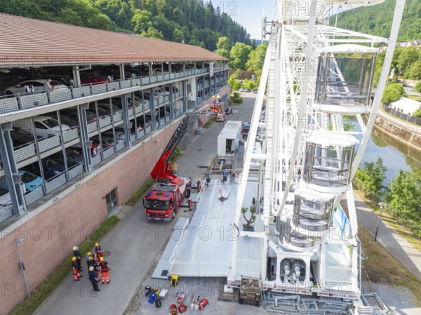 Fire engines and workers next to a Ferris wheel in an urban environment, fire brigade exercise for gondola rescue, Germany