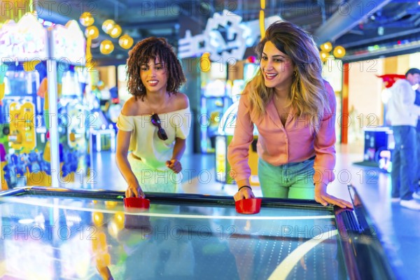Two female friends enjoying a lively game of air hockey in a vibrant amusement arcade filled with colorful lights and excitement