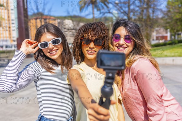 Multi ethnic women enjoying summer urban vacation, using action camera to film themselves, capturing joyful moments and memories together
