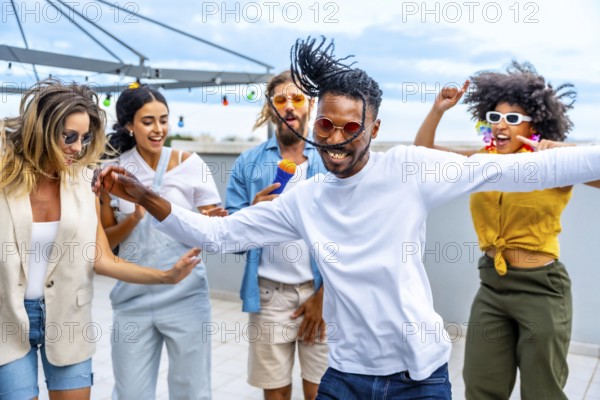 Young people dancing and singing joyfully at a vibrant rooftop party, enjoying music and celebrating summer together with friends