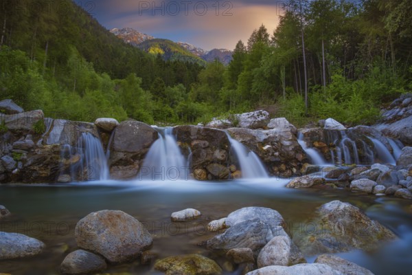 View of a waterfall of the Rio Plima stream in the evening light, long exposure, landscape photo, nature photo, landscape format, forest, trees, Dolomites, South Tyrol, mountains, Laces, Morter, Italy