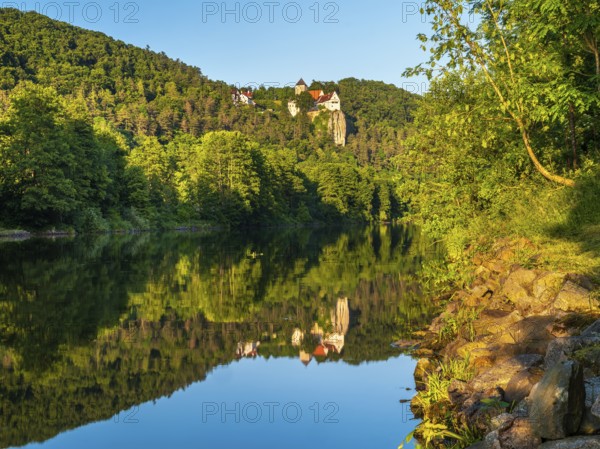 Prunn Castle on a steep cliff above the Altmühl Valley in the evening light, reflection in the river Altmühl as part of the Main-Danube Canal, near Riedenburg, Altmühl Valley nature park Park, Lower Bavaria, Germany