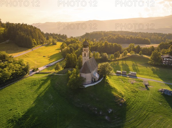 Church in a gentle hilly landscape with rich greenery and warm sunset light