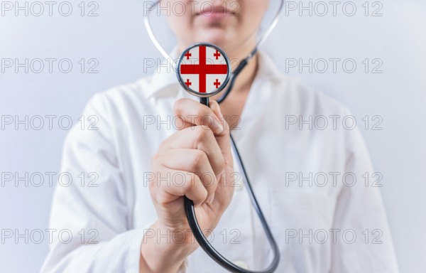 Female doctor holding stethoscope with Georgia flag. National health system of Georgia