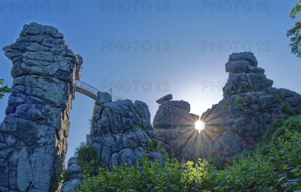 The morning sun shines through an opening in the Externsteine. The Externsteine, a sandstone rock formation around 40 metres high in the Teutoburg Forest, are a natural sight and are a protected natural and cultural monument. They are regarded as a place of power and are considered to have special cultural and historical significance. Horn-Meinberg, North Rhine-Westphalia, Germany