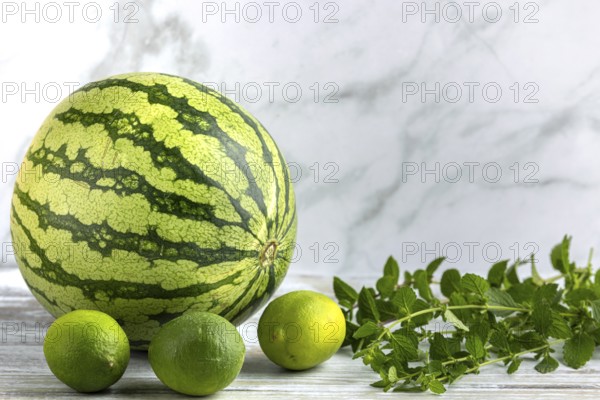 Watermelon and limes with mint leaves on a wooden surface