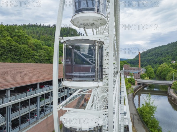 Ferris wheel with gondolas next to a building and a river, Ferris wheel construction for the 950th anniversary of the town of Calw, Black Forest, Germany