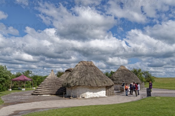 Tourists visit the replicas of Neolithic houses at the Stonehenge visitor centre. Amesbury, Wiltshire, South England, Great Britain