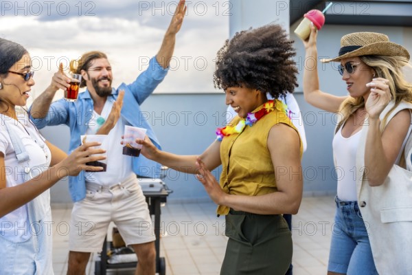 Cheerful friends dancing and enjoying drinks at a rooftop party, celebrating friendship and good times