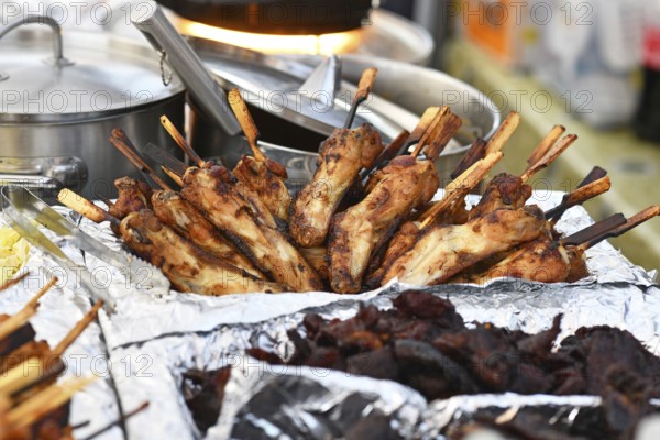 Grilled Thai chicken skewers on display at street food market. Traditional gai yang with wooden sticks