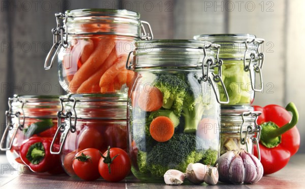 Jars with marinated food and organic raw vegetables