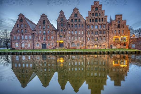 The historic salt warehouse reflected in the Trave river at dusk, seen in Lübeck, Germany