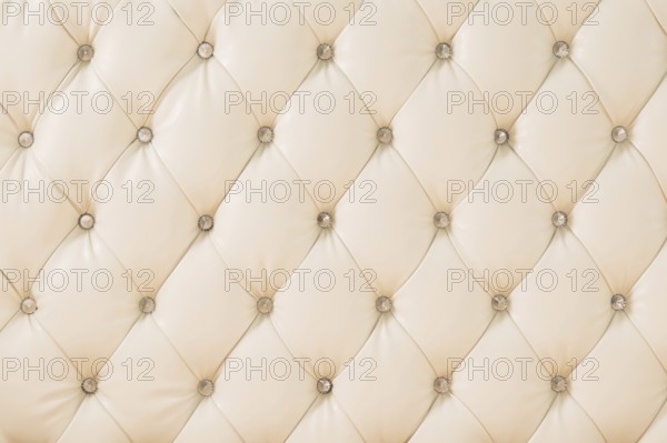 Beige soft tapestry pattern background with symmetrical buttons on the corners of diamonds. Soft and expensive furniture elements. Luxury background