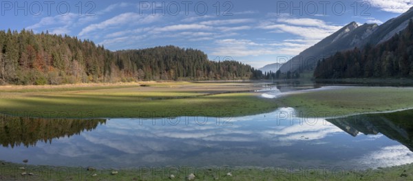 Autumn color mountain landscape and lake in the Swiss Alps with reflections and forest
