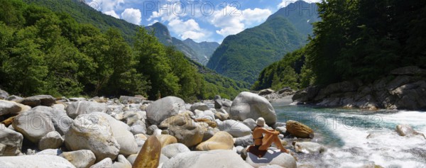 young lady sunbathing by a rocky alpine foothills stream in the remote valley of Val Verzasca, near lavertezzo, Ticino