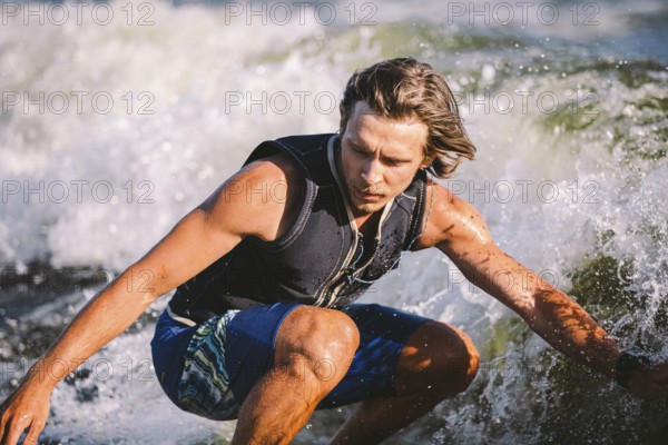 A man is surfing on a surfboard drawn by a motor boat above the wave of the boat. Weixerfer is engaged in surfing, entertainment, leisure, water sports. Athlete glides on the waves on the board