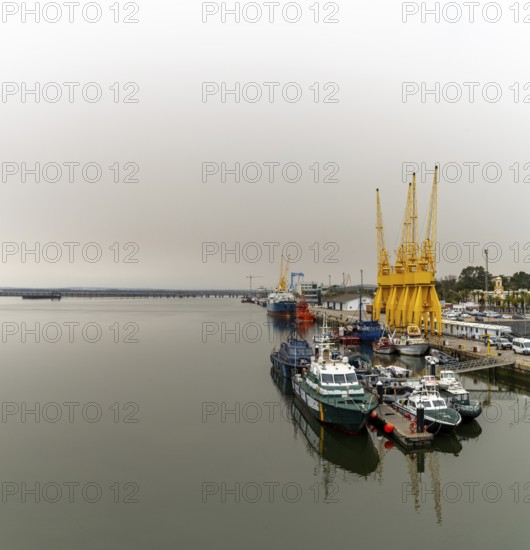 Huelva, Spain - 15 March, 2022: calm Rio Tinto River with harbor cranes and Guardia Civil police boats in the harbor of Huelva