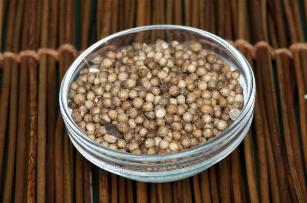 Dried coriander in a bowl on wooden base