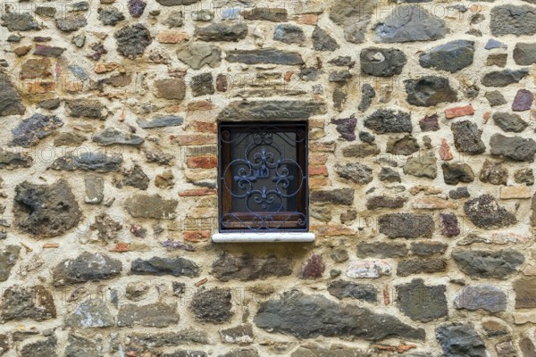Cloudy autumn day in Tuscany. The small town of Montalcino. The beautiful decor element of a small window - metal window grill. The concept of cognitive, active and photo tourism