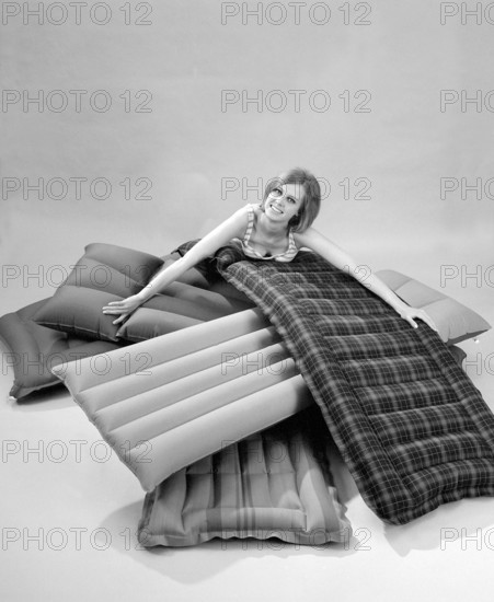 1960s. A young woman wearing a bikini, in a photographers studio with different types and brands of air mattresses. A picture taken to illustrate the new ones available in different shapes and colors to use the upcoming summer. Sweden 1967. Conard ref 5447