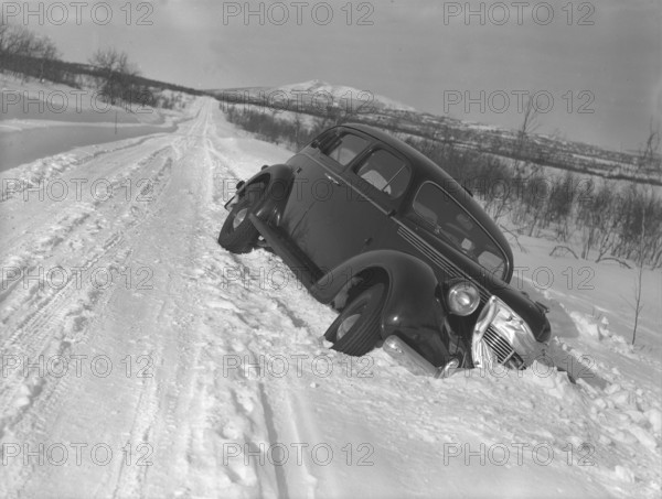Winter driving in the 1930s. A car has skidded of the snowy road down and is stuck in the snow beside the road. Sweden 1939. Photo Kristoffersson ref 3-1