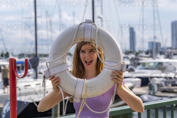 A gorgeous redhead model enjoys the perfect summer weather at a local marina, surrounded by boats of all kinds in the background, their reflections dancing on the water under the bright, sunny sky, Milwaukee, United States of America