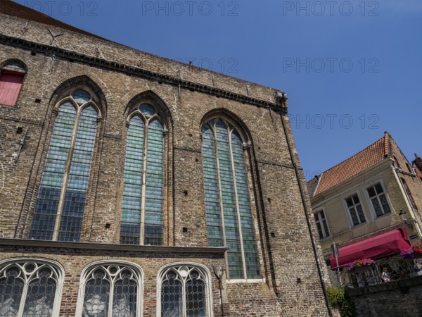 Large brick building with high pointed arch windows and clear blue sky, Bruges, Belgium