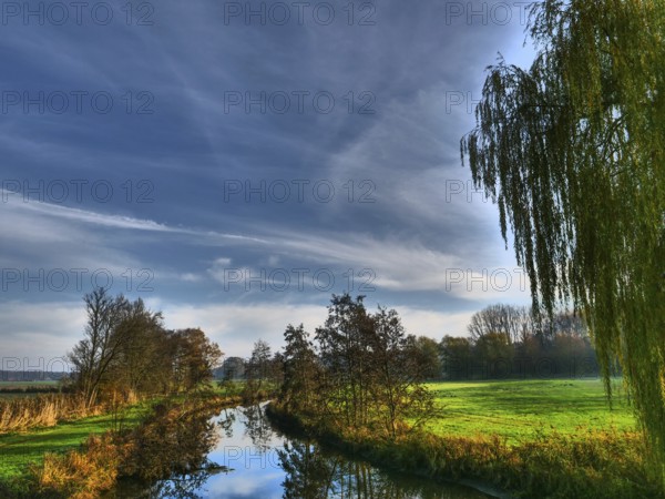 A calm river under a clear sky with few clouds and surrounded by trees, Borken, münsterland, germany
