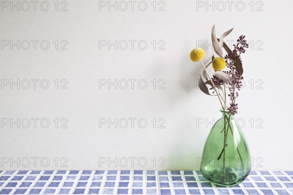 Vase of dry flowers on blue ceramic mosaic tile table. white wall background. Home interior