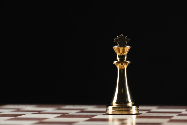 Golden king chess figure standing on chessboard. Intellectual and tactic game. Strategy planning, leadership and teamwork business concept. Close-up one gold chess piece on black background