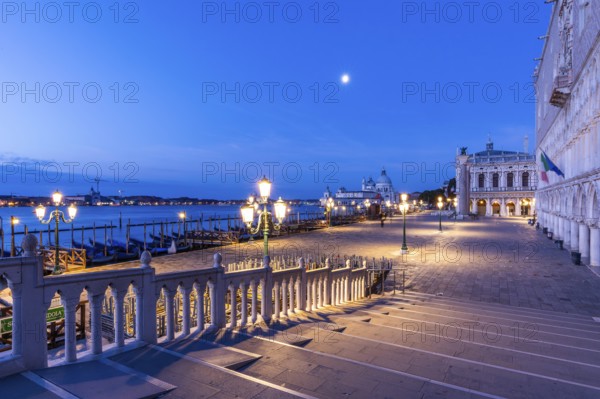 Bridge over a canal, blue hour, moon behind over the church Maria della Salute, Venice, Veneto, Italy