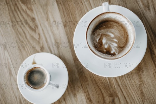 Top view of a cappuccino with latte art and an espresso on a wooden table