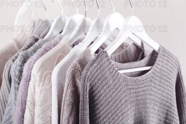 Warm knitted, autumn, winter clothes hanging on a rack, trending concept, pastel colours