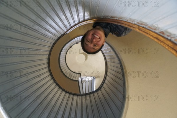 Woman looking down on the top a spiral staircase, circular architectural shape, San Diego, California, USA. November 10th, 2020