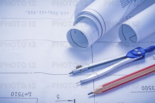 Compass pencil and two rolled up white blueprints copyspace